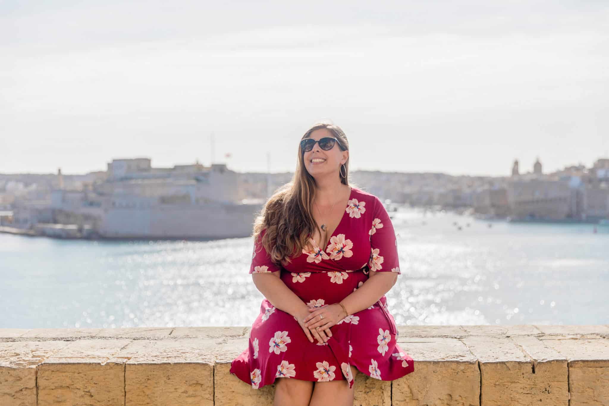 Hannah Logan smiling while sitting on a wall in Valetta, Malta