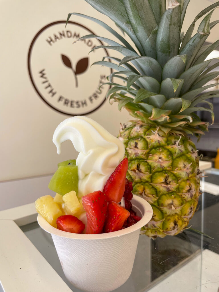 Tamata frozen yogurt in a cup beside a pineapple