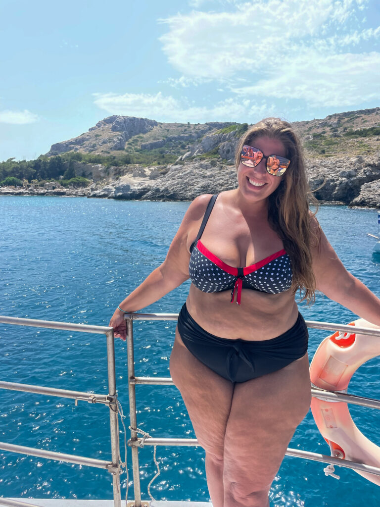 Hannah posing on the side of a boat in bikini off the coast of Rhodes, Greece