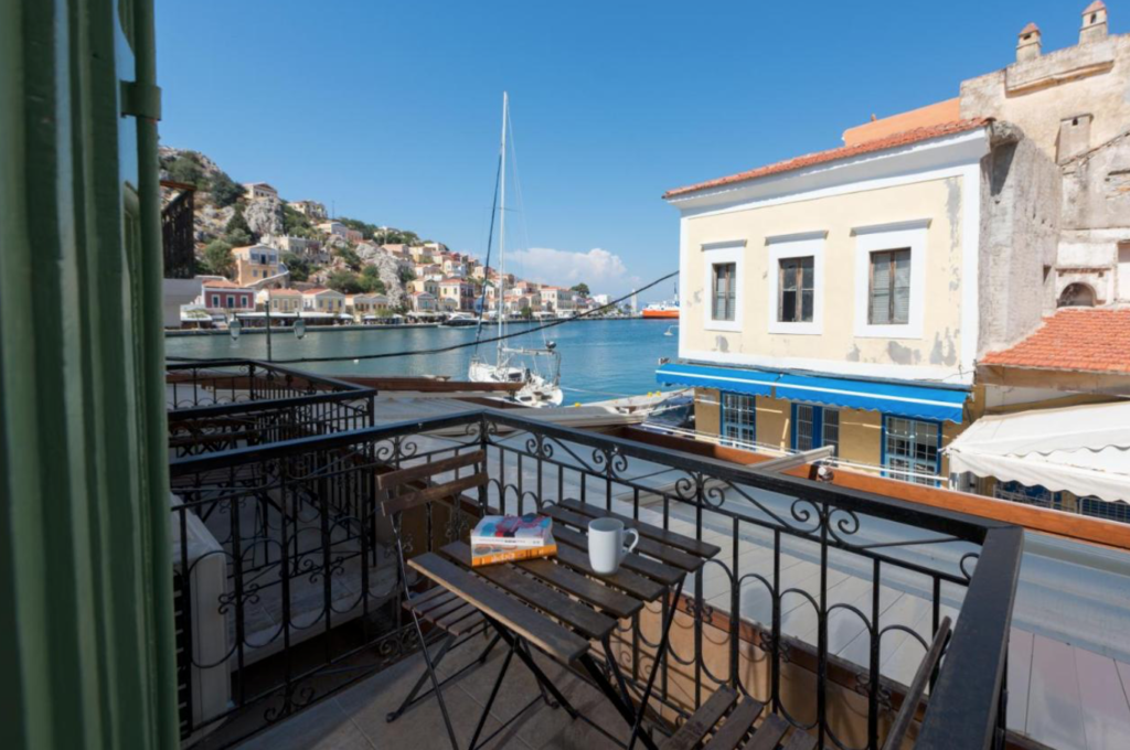View of Symi Harbour from a balcony with two small chairs and a table