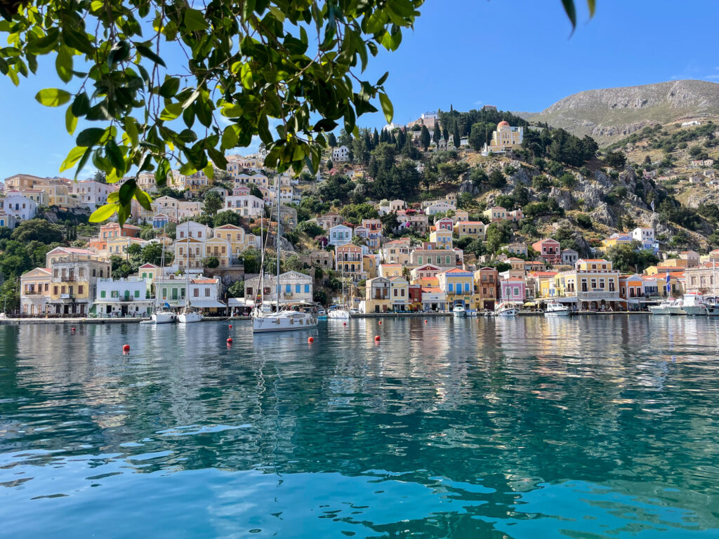 Symi harbour as seen through the leafy branches of a tree
