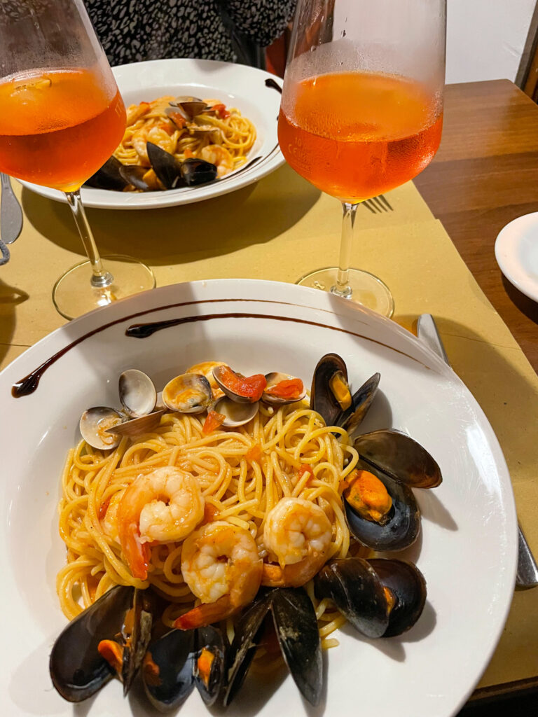 a plate of seafood spaghetti and a spritz to drink