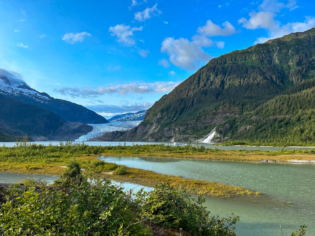 View of Mendenhall Glacier in Juneau Alaska against a blue sky with Nugget falls waterfall off to the right