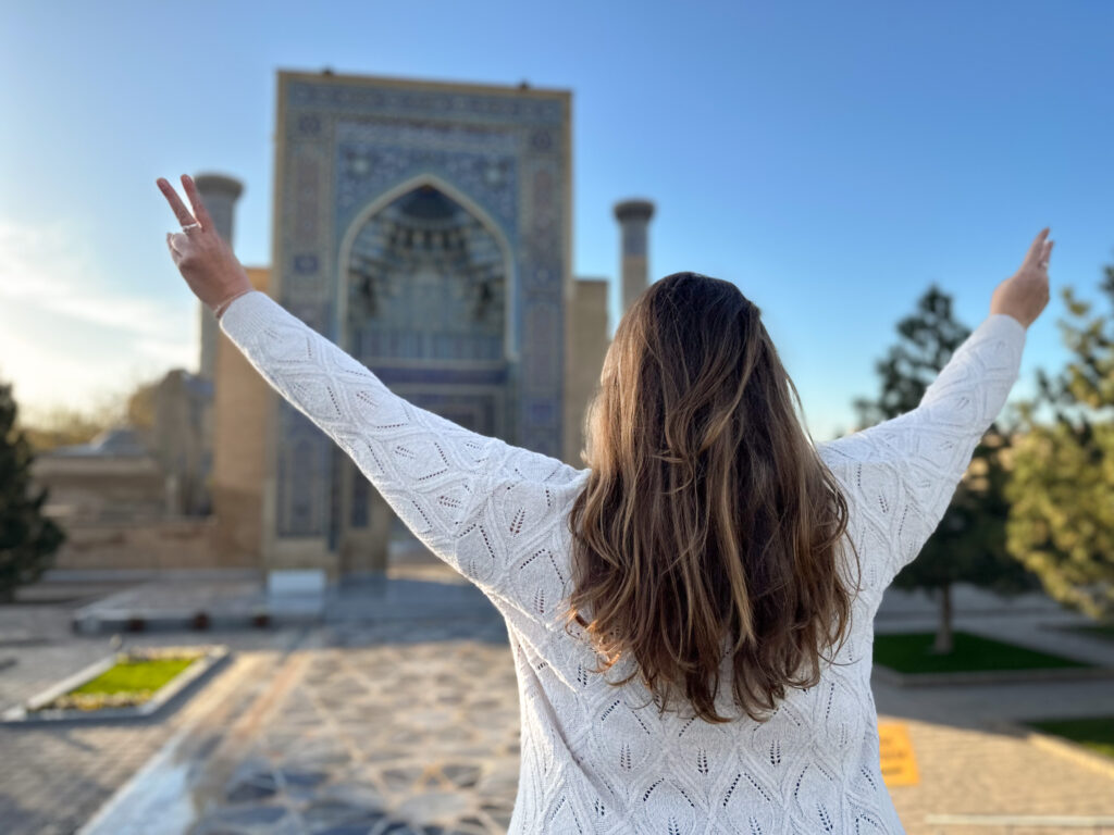 Hannah with her arms out facing a tiled mausoleum