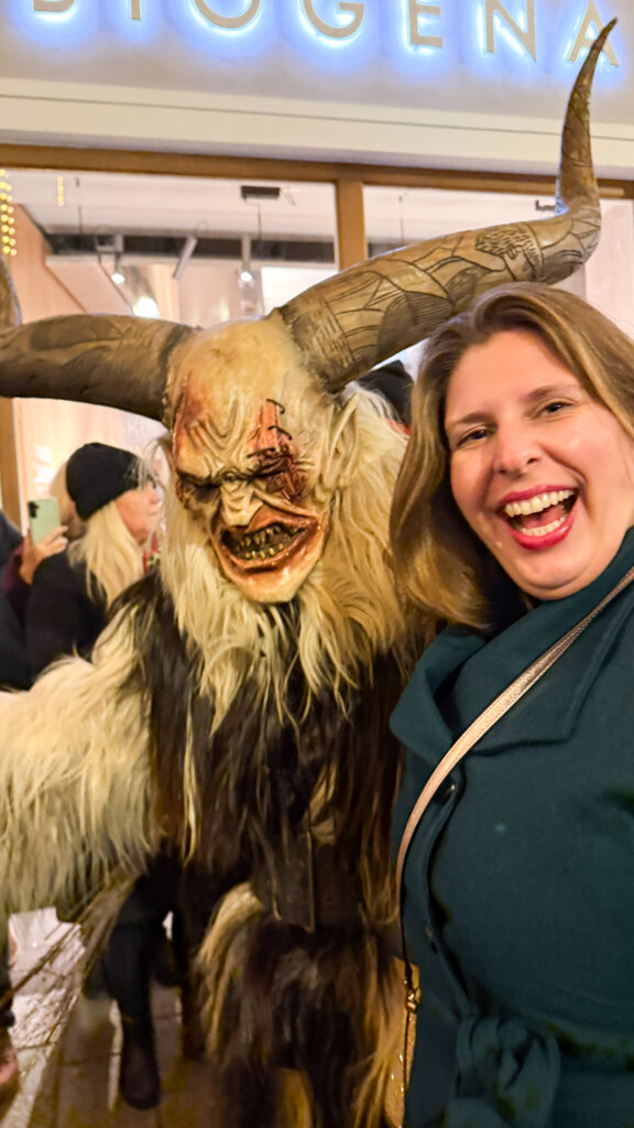 Hannah laughing as a man dressed as Krampus lurks behind her